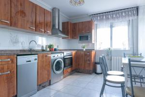 une cuisine avec des armoires en bois et une laveuse et une sécheuse dans l'établissement El estanque, à Galizano