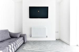a living room with a couch and a tv on the wall at Local City Centre 3 Bedroom House in Clydach
