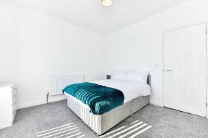 a white bedroom with a bed with a green blanket at Local City Centre 3 Bedroom House in Clydach