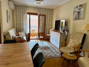 un salon avec une table, des chaises et une télévision dans l'établissement MARESOL - apartment close to the beach and restaurants, à San Pedro del Pinatar
