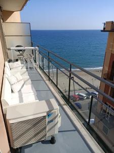 balkon z białą kanapą i plażą w obiekcie Casa di Noemi - Seafront with parking w mieście Savona