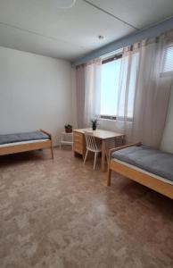 a room with two beds and a table and a desk at Miilunhovi kolmio in Petäjävesi