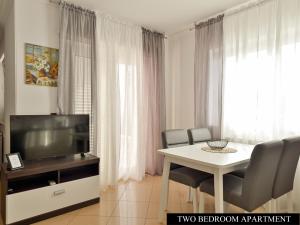 salon z telewizorem i stołem z krzesłami w obiekcie Apartments Angela w mieście Umag