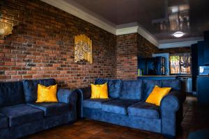 Dos sofás azules en una habitación con una pared de ladrillos. en Ikhthus Accommodation N, en Hibberdene