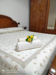a bed with towels and a bouquet of flowers on it at Casa Cesa in Selargius