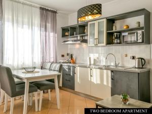 kuchnia ze stołem, krzesłami i zlewem w obiekcie Apartments Angela w mieście Umag