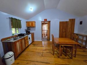 a kitchen with a wooden table and a wooden floor at Cotton Tree Cabin at Freshwater Creek Cabanas in Hopkins