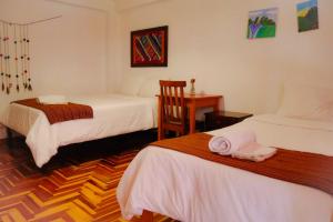 a hotel room with two beds and a desk at shanti hotel in Pisac