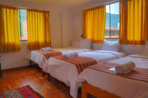 three beds in a room with yellow curtains at shanti hotel in Pisac