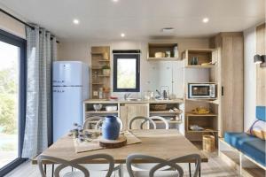 a kitchen with a table and chairs and a refrigerator at Camping LE MOULIN DE CAUDON in Domme