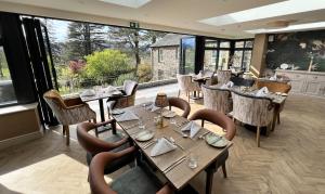 ein Restaurant mit Tischen und Stühlen und einem großen Fenster in der Unterkunft Ravenstone Lodge Country House Hotel in Keswick