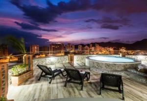 a patio with chairs and a swimming pool at night at Apartamento Terrazas Tayrona in Gaira