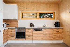 a kitchen with wooden cabinets and a sink at FeWo Nocky- SAUNA- Wandern- Berge- Auszeit- Liftnähe in Turracher Hohe +6 photos