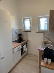 a kitchen with white cabinets and a sink and two windows at Modern Living - Im Grund in Spaichingen