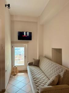 a living room with a couch and a tv on the wall at SyrasView in Ermoupoli