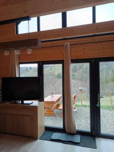 uma sala de estar com televisão e uma grande janela em Domki RESET em Polańczyk