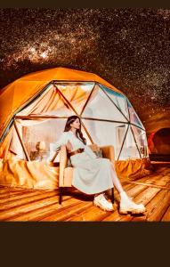 a woman is sitting in front of a tent at Revan Rum Luxury Camp in Wadi Rum