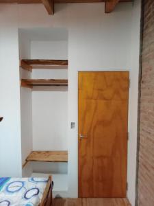 Cette chambre comprend un lit et une porte en bois. dans l'établissement CABAÑA PRIVADA NALÚ 2, Villa Ciudad Parque a 150m Río Los Reartes, à Villa Ciudad Parque