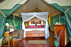 a bedroom in a tent with a bed and a desk at Samburu Intrepids Tented Camp in Archers Post
