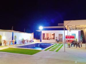 a villa with a swimming pool at night at Sky Blue Farm in Umm Jawzah
