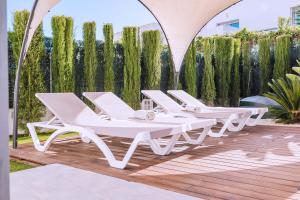 a group of white lounge chairs on a wooden deck at Casa Coco Stylisches Beachhouse mit Pool & Sundeck Els Poblets Denia in Els Poblets