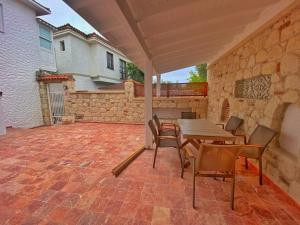 Un patio con mesa y sillas y un muro de piedra. en GK HOUSe, en Alacati