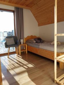 a bedroom with a bed and a chair and a window at Domki Na Brzyzku - Domek w górach z balią z jacuzzi in Zakopane