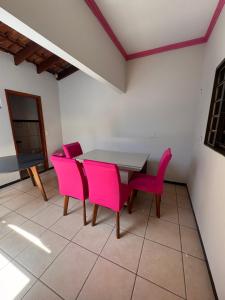 a dining room with pink chairs and a table at Colibri Inhouse Santa Cruz in Rondonópolis