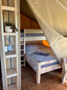 a couple of bunk beds in a room at Luxe glamping tenten aan het water in Wommels