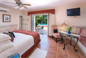 a bedroom with a bed and a tv and a patio at Little Arches Boutique Hotel - Adults Only in Christ Church
