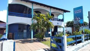 a white building with a palm tree in front of it at Hostel Itapeva in Itapoa