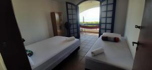 two beds in a room with a view of a balcony at Hostel Itapeva in Itapoa +16 photos