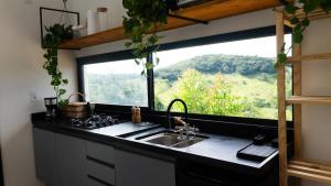 a kitchen with a sink and a large window at Chalé Monte Lumier in Tiradentes
