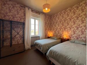 Un dormitorio con dos camas y una ventana. en La Colombière - Appartement Villa front de mer, en Granville