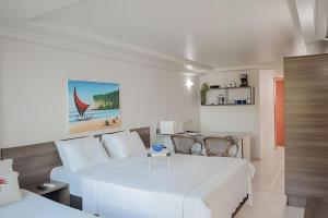 a white bedroom with a white bed and a table at Refúgio à Beira-Mar Cabo Branco! Blue Sunset #501 in João Pessoa