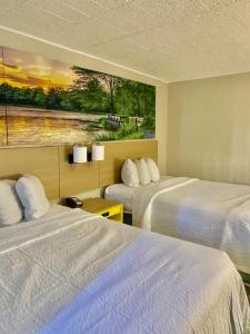 a hotel room with two beds and a painting on the wall at Days Inn by Wyndham Scranton PA in Dickson City +13 photos