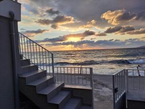 a stairway leading to the beach with a sunset at Cozy SeaView apartment in Paralía Kímis