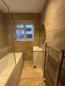a bathroom with a tub and a sink and a mirror at The Modern Retreat in Barnet +33 photos