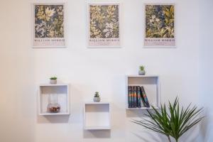 una pared blanca con tres cuadros en la pared con una planta en ARK Apartaman Sárvár, en Sárvár