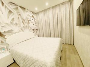 a bedroom with a white bed with a floral wall at Hope House in Villasimius