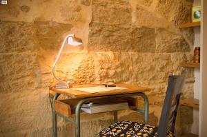 a desk with a lamp on it next to a stone wall at La suite du Duché in Uzès