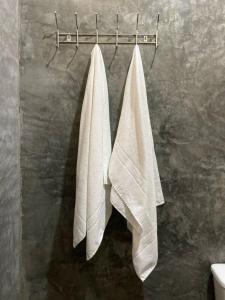 two white towels hanging on a towel rack in a bathroom at Recanto Caiçara Caraiva - Chalé, Quartos privativos e Compartilhado in Porto Seguro
