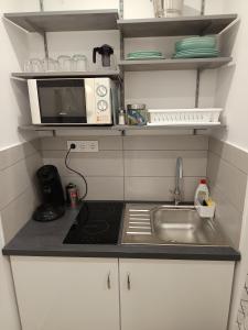 a small kitchen with a sink and a microwave at City-Garzon in Kaposvár