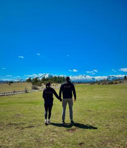 two people walking in a field holding hands at Eternum Glamping in Žabljak