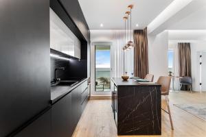 a kitchen with black cabinets and a counter with a table at Exotic Sunrise View in Infinity Pool & Spa Resort in Mamaia Sat/Năvodari