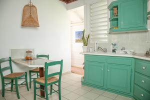 a kitchen with blue cabinets and a table and chairs at LA DILETTANTE - Maison Créole de 130m2 - Clim - Tout à Pied in Terre-de-Bas