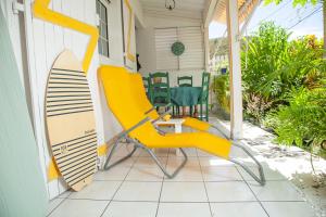 a yellow chair and a surfboard on a porch at LA DILETTANTE - Maison Créole de 130m2 - Clim - Tout à Pied in Terre-de-Bas