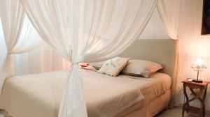 a bedroom with a bed with white curtains at LA DILETTANTE - Maison Créole de 130m2 - Clim - Tout à Pied in Terre-de-Bas