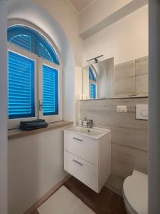 un bagno con lavandino bianco e due finestre di Residence Quedar a Melfi