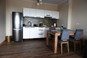 a kitchen with a table and a refrigerator at Apartament Podmiejska in Kalisz